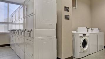A laundry room with multiple washers and dryers, a front desk, and a window providing natural light.