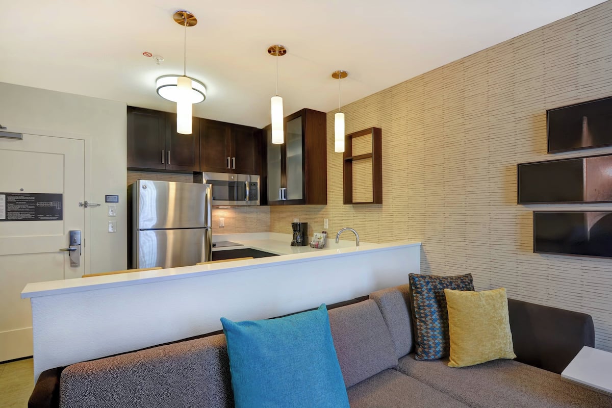 A modern kitchen with stainless steel appliances, a white countertop, and pendant lighting.