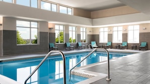 Ein Schwimmbecken mit klarem, blauen Wasser, umgeben von Liegestühlen und einem gefliesten Boden.
