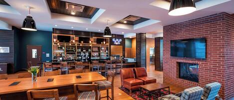 A modern bar area with a brick fireplace, wooden furniture, and a bar counter.