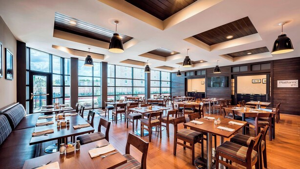 A spacious restaurant with high ceilings, large windows, and modern lighting fixtures.