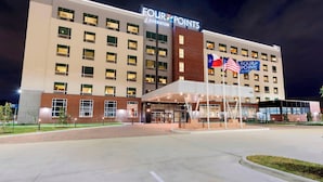 A Four Points by Sheraton hotel with a modern facade, large windows, and a well-lit entrance area.