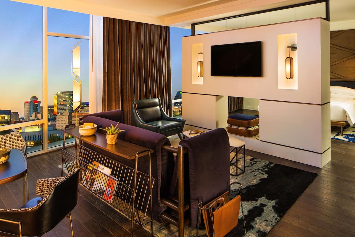 Un salon moderne avec vue sur la ville, un téléviseur à écran plat et un coin repas comprenant une table et des chaises.