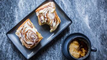 Two pastries on a dark plate with a cup of coffee beside it.