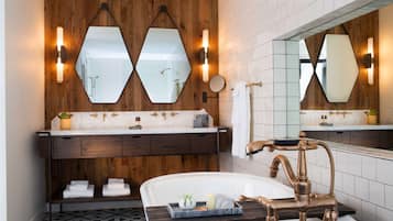 Ein modernes Badezimmer mit einem Holzbadezimmer-Möbelstück, einer freistehenden Badewanne und zwei an der Wand befestigten Spiegeln.