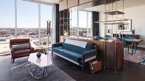 A modern living room with a large window, a sofa, a coffee table, and a dining area with chairs and a table. - Thompson Nashville, by Hyatt (Nashville)