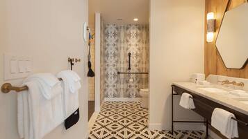 A modern bathroom with a geometric patterned floor, a large mirror, and a dual sink vanity.