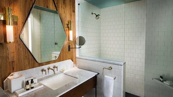 Ein modernes Badezimmer mit einem Holzausleger, einem großen Spiegel, einer Glasdusche und weiß gefliesten Wänden.