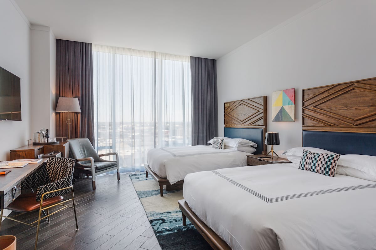 Une chambre d’hôtel avec deux lits, un bureau, une chaise et une télévision.