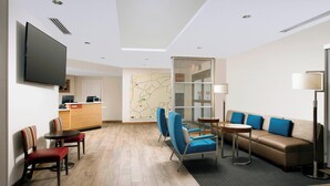 A modern hotel lobby with a reception desk, seating area, and a large flat-screen TV. - TownePlace Suites by Marriott Alexandria Fort Belvoir (Alexandria)