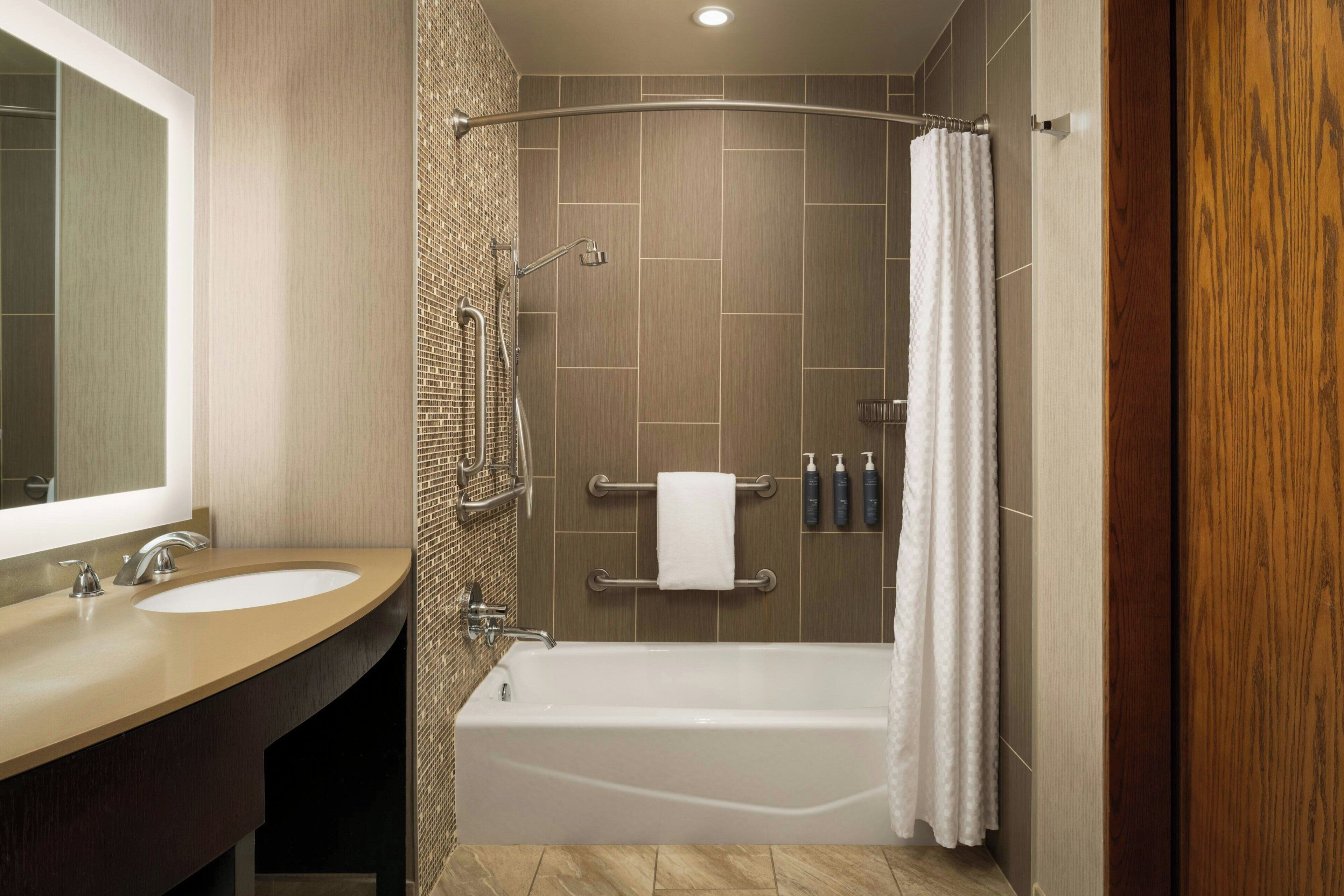 A modern bathroom with a bathtub, a vanity with a sink, and a mirror.