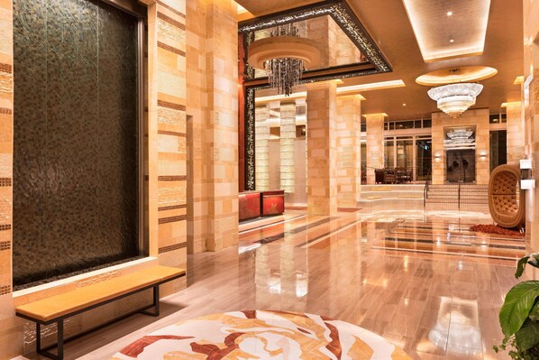 A spacious lobby with a polished floor, a bench, a large decorative wall, and a reception area with a red counter. - The Westin Nashville (Nashville)