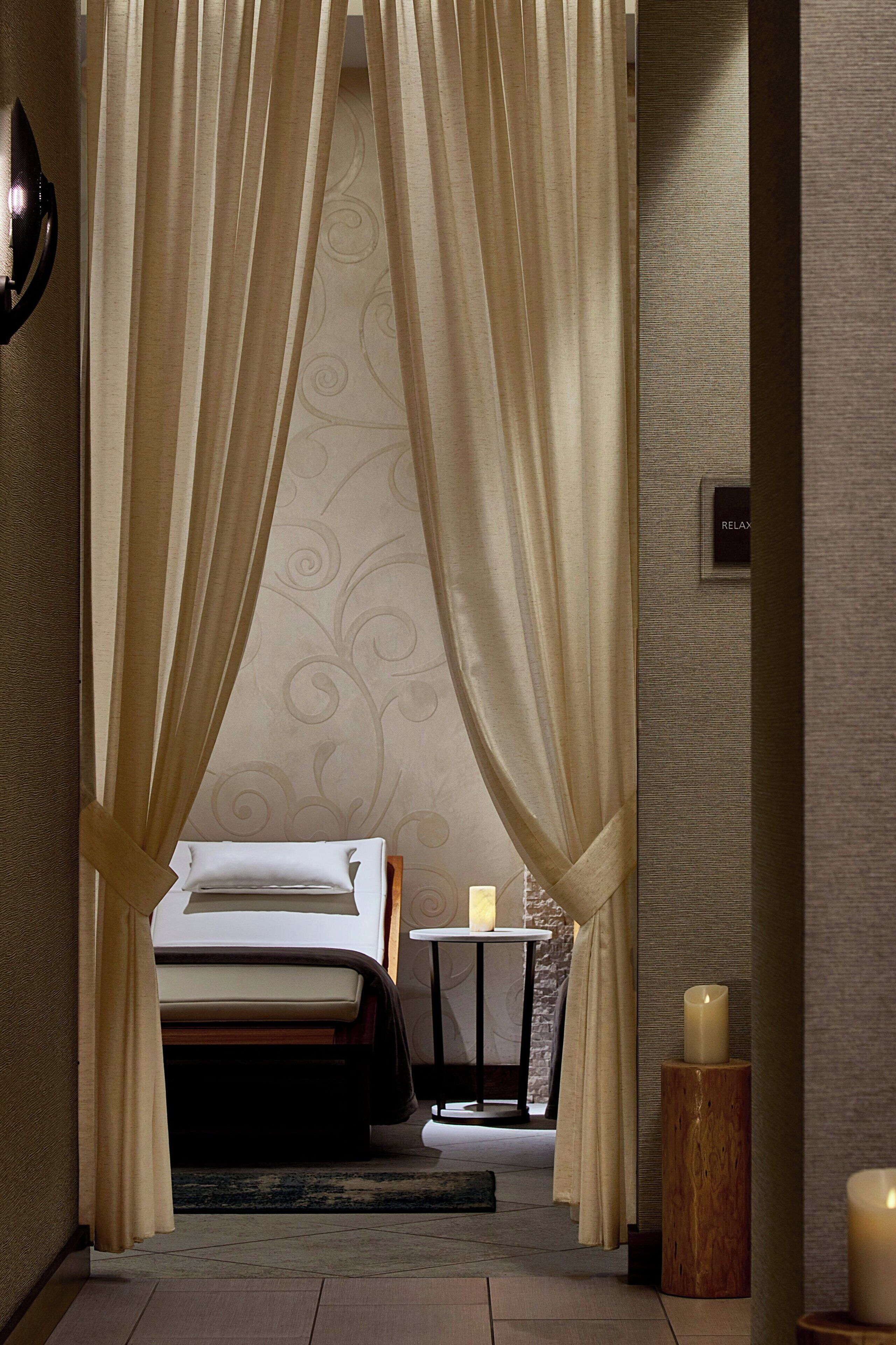 A hotel room with a bed, a small table with candles, and a decorative wall.