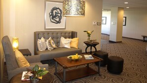 A lobby with a sofa, armchair, coffee table, and a decorative lamp. - Hotel At Batavia Downs (Batavia)