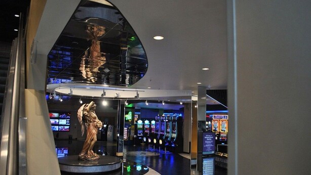 A modern interior with a central circular platform, a statue, and a row of slot machines in the background. - Hotel At Batavia Downs (Batavia)