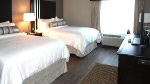 A hotel room with two beds, a desk, a television, and a window with curtains. - Hotel At Batavia Downs (Batavia)
