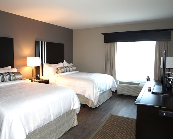 A hotel room with two beds, a desk, a television, and a window with curtains. - Hotel At Batavia Downs (Batavia)