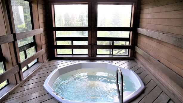 A hot tub in a wooden cabin with a view of trees through large windows. - Buffalo Ridge 2 Bed Loft (Silverthorne)