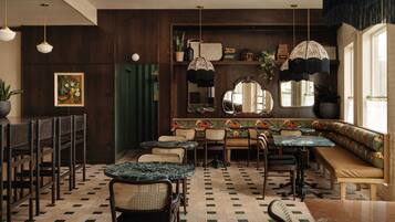 A restaurant interior with wooden paneling, a green curtain, and a variety of seating including tables and benches.