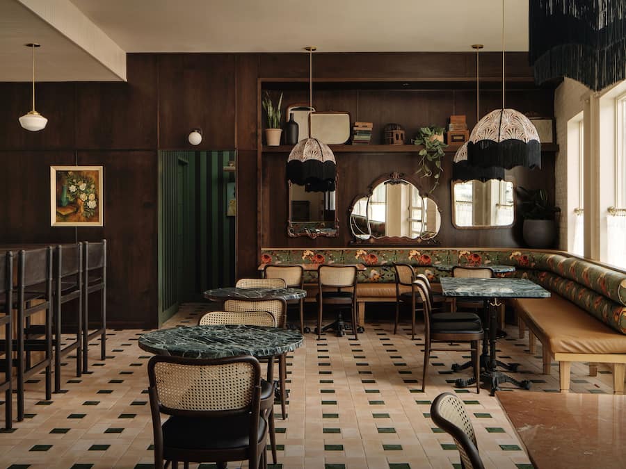 A restaurant interior with wooden paneling, a green curtain, and a variety of seating including tables and benches.