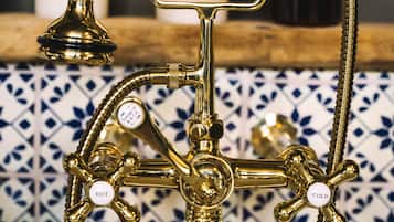 Un accesorio de baño de bronce con un mando blanco, caño de agua fría y caliente, y cabezal de ducha.