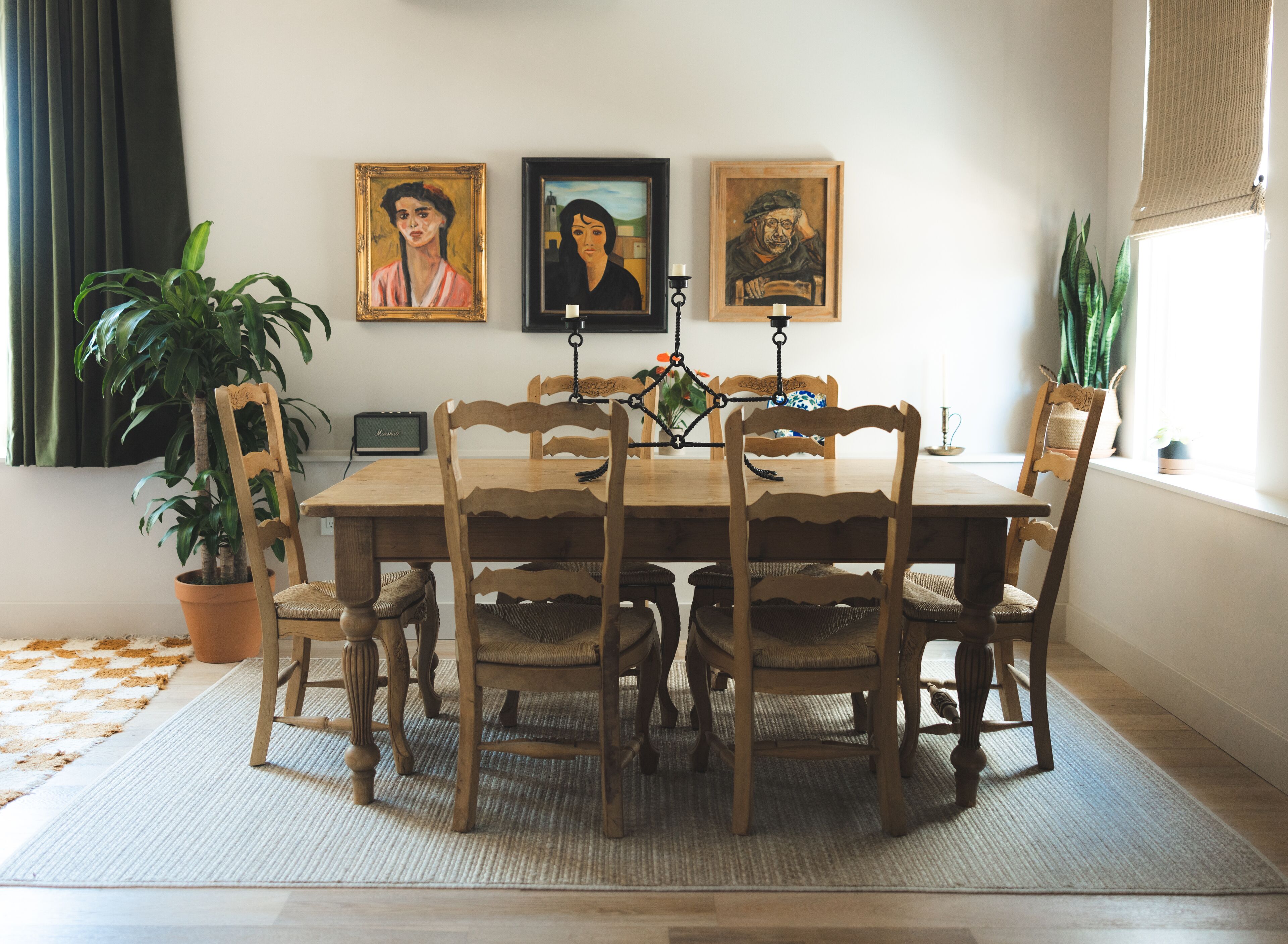 Ein Esszimmer mit Holztisch und -stühlen, umgeben von gerahmten Bildern, einer Topfpflanze und einem Radio.