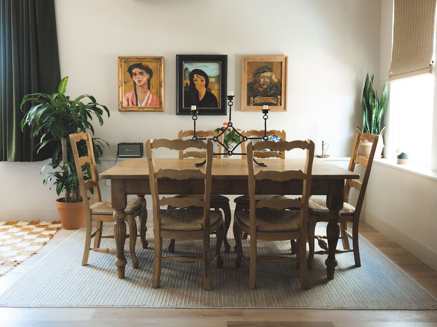 Ein Esszimmer mit Holztisch und -stühlen, umgeben von gerahmten Bildern, einer Topfpflanze und einem Radio.