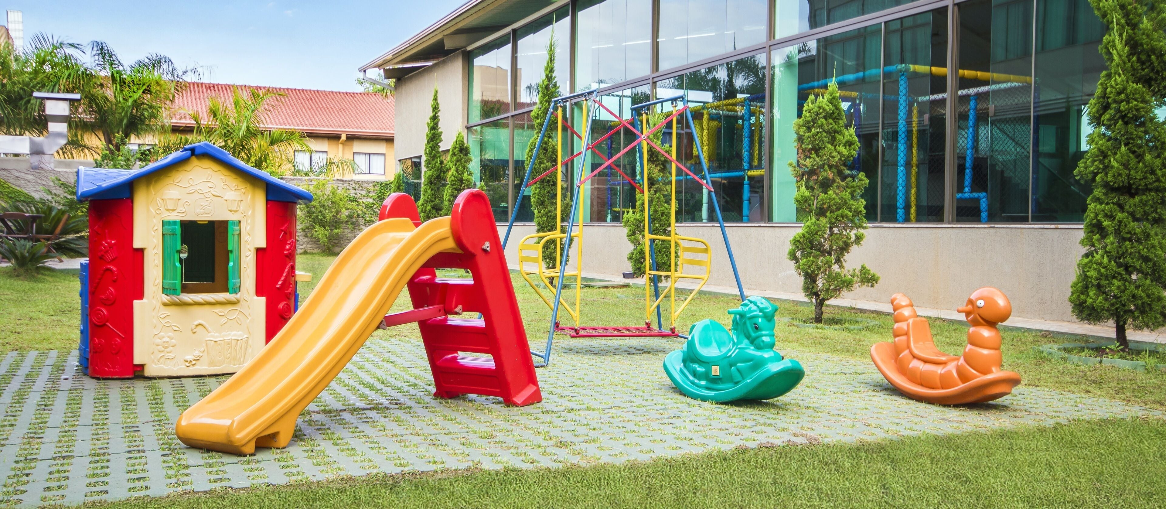 Un parque infantil con tobogán, columpios y una casita.