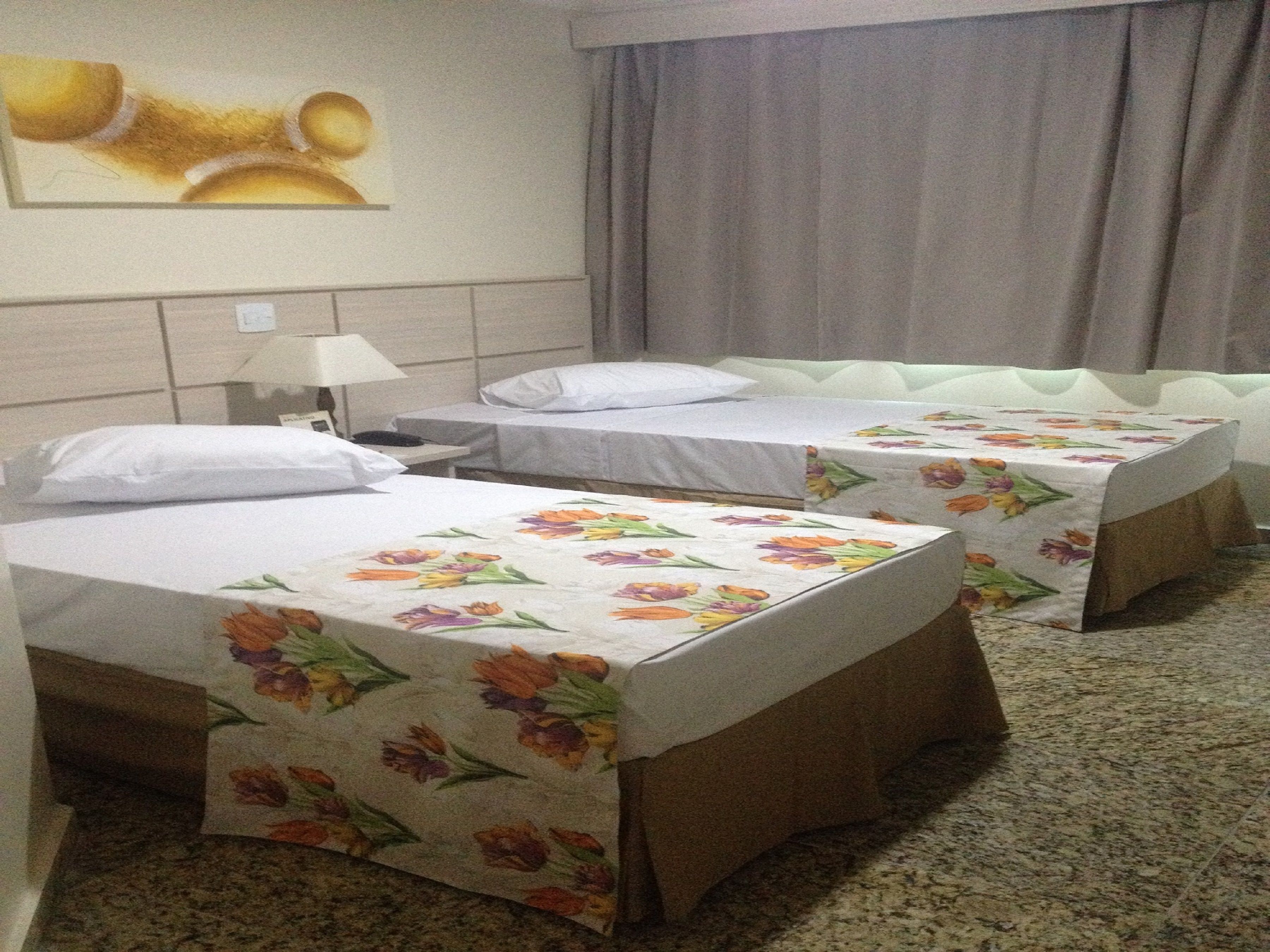 Ein Hotelzimmer mit zwei Einzelbetten, einem Nachttisch, einer Lampe und einem Bild an der Wand.