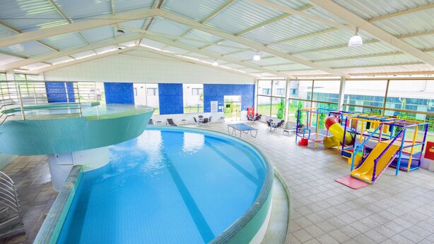 An indoor swimming pool with a diving area, lounge chairs, and a children's play area. - Hotel Golden Park Sorocaba & Convenções - by Nacional Inn (Sorocaba)