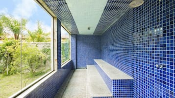 Casa de banho com azulejos azuis e janela com vista para um jardim.