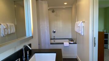 Une salle de bain moderne avec un lavabo sur un plan de toilette noir, un grand miroir et un espace douche.