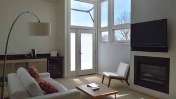 A modern living room with a sofa, a coffee table, a TV, and a fireplace.