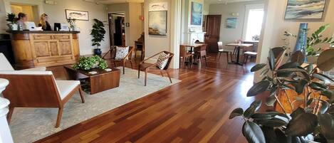 A spacious living area with wooden flooring, a central seating area with chairs and a coffee table, a kitchen area with a counter and cabinets, and a dining area with a table and chairs.