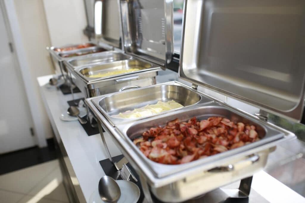 A buffet line with various food items in stainless steel containers.