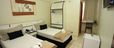 Habitación de hotel con dos camas, un escritorio, una silla, un televisor y un refrigerador pequeño.