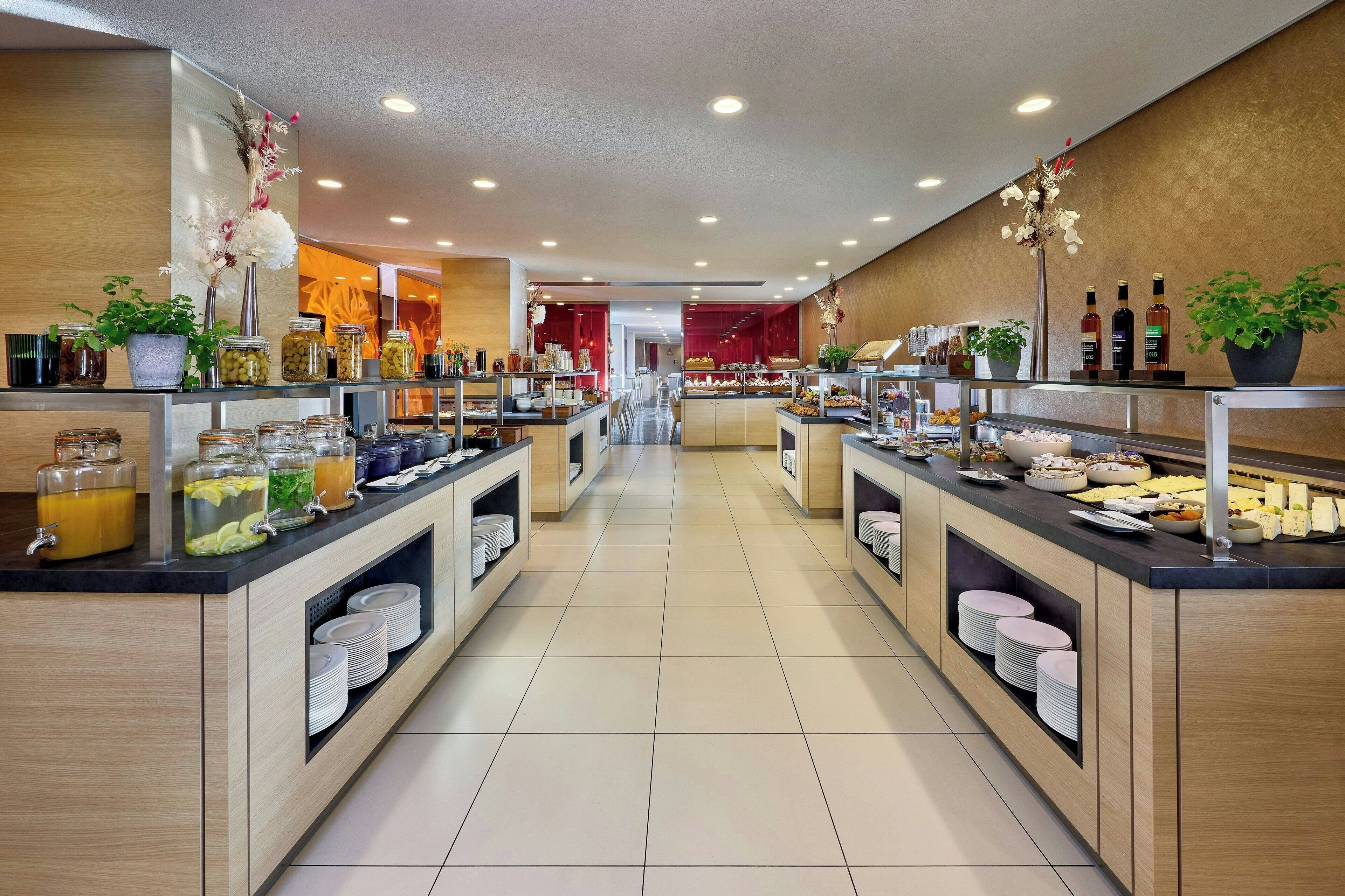 Un buffet moderne, avec plusieurs points de service, des récipients en verre contenant les aliments et des plantes décoratives.