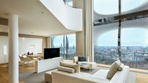 Ein modernes Wohnzimmer mit großem Fenster, Flachbildfernseher, einer Couch und einem Essbereich.