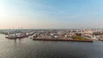 Ein Industriehafen mit Kränen, Tankspeichern und einem großen Schiff, das vertäut ist.