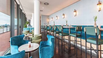 A modern restaurant with teal seating, large windows, and decorative wall sconces.
