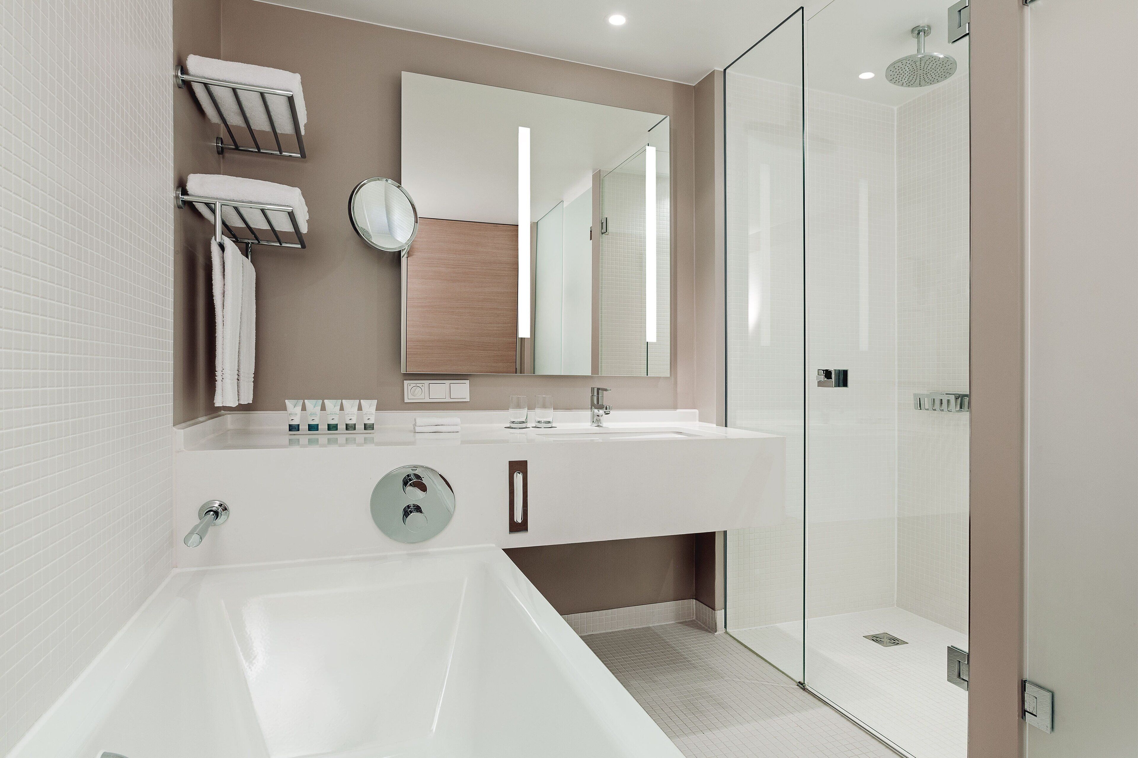 Un baño moderno con una bañera grande, una ducha con mampara de vidrio y un lavamanos con espejo y toallero.