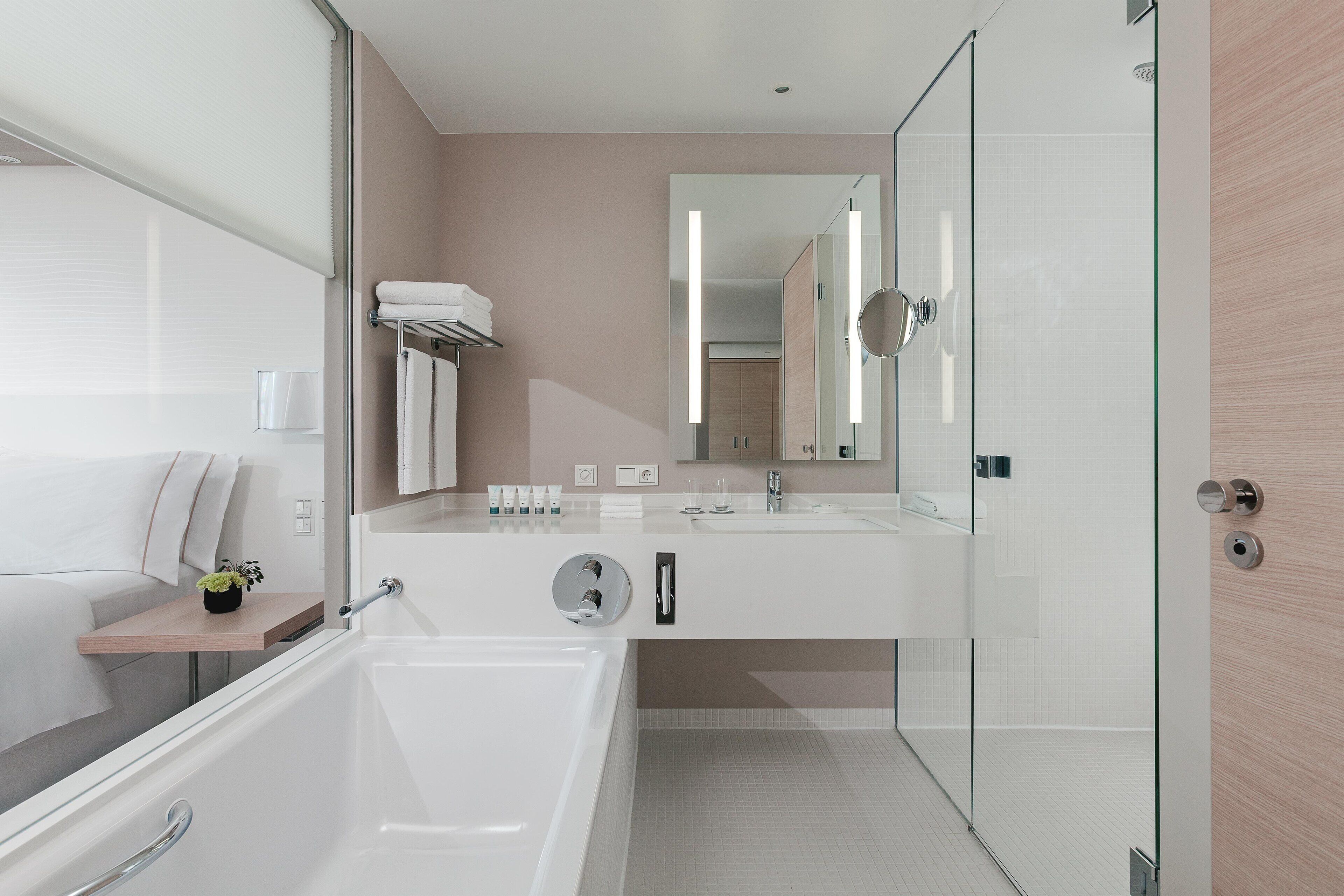 Un baño moderno con cabina de ducha de vidrio, una bañera grande y un lavamanos con espejo.