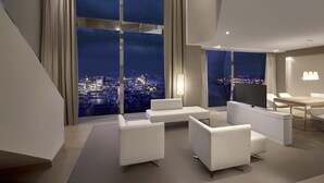 Une chambre d’hôtel moderne avec vue sur la ville, une grande fenêtre, un téléviseur à écran plat et un coin repas.
