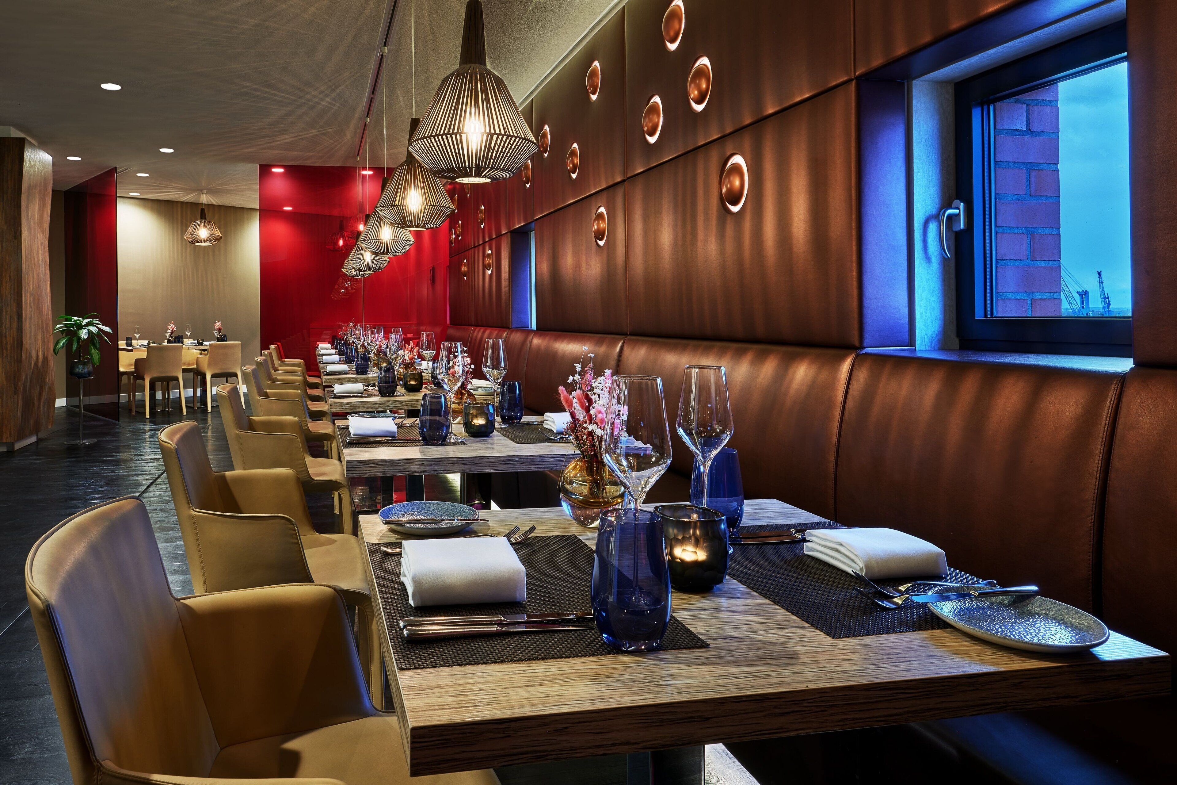 Un restaurante con varias mesas, cada una dispuesta con cubiertos, platos y vasos.