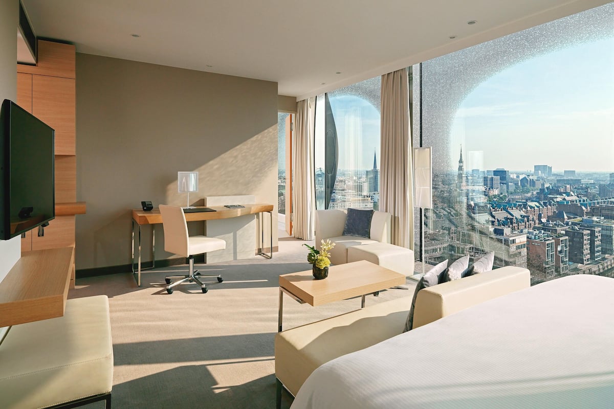 Une chambre d’hôtel moderne avec vue sur la ville, un bureau, un canapé et un lit.