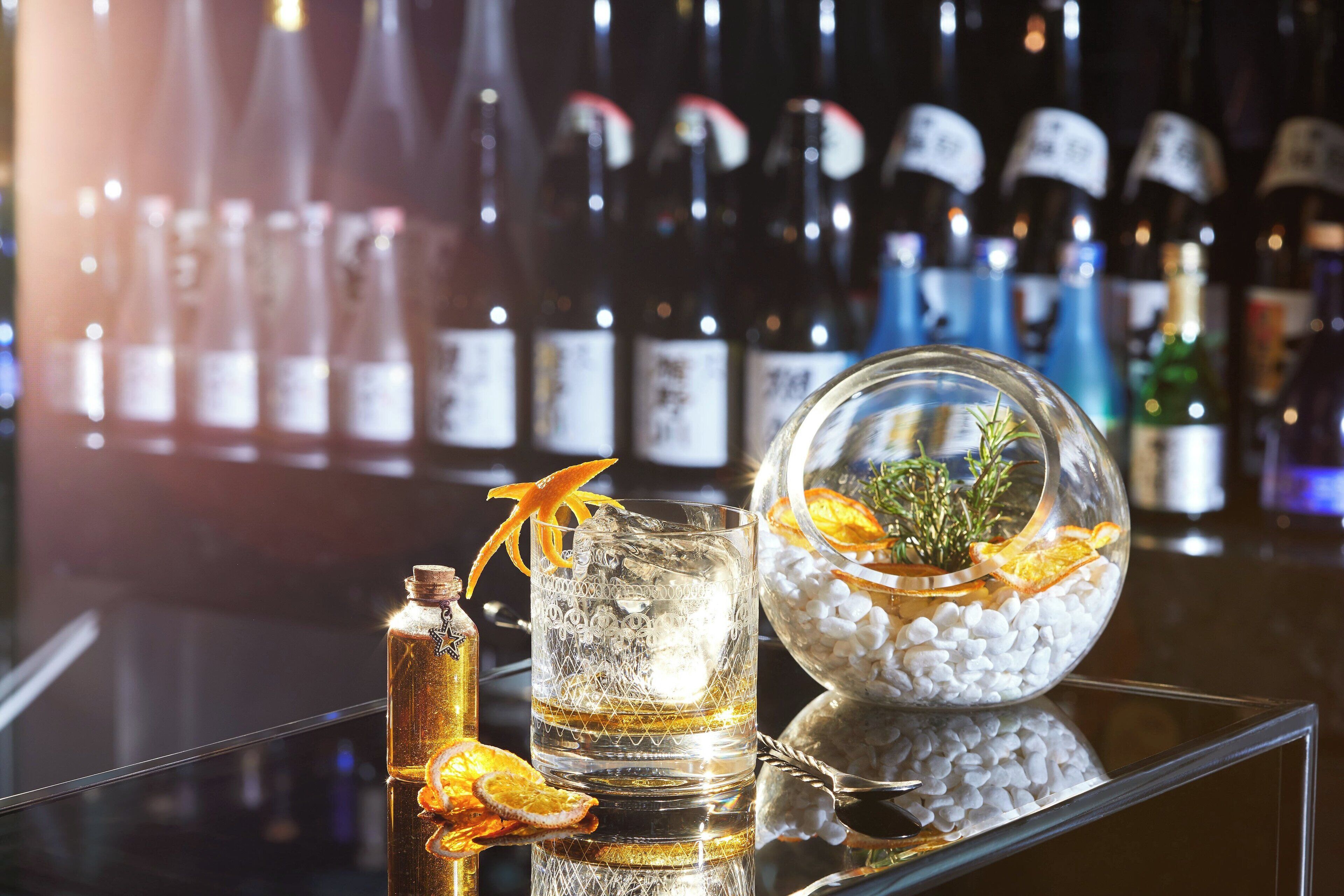 Un bar con una variedad de botellas, un vaso con hielo y un adorno.