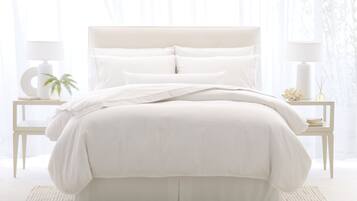 A neatly made bed with white bedding and pillows, flanked by two bedside tables with lamps and decorative items.