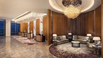 A luxurious lobby with a grand chandelier, plush seating, and a reception desk.