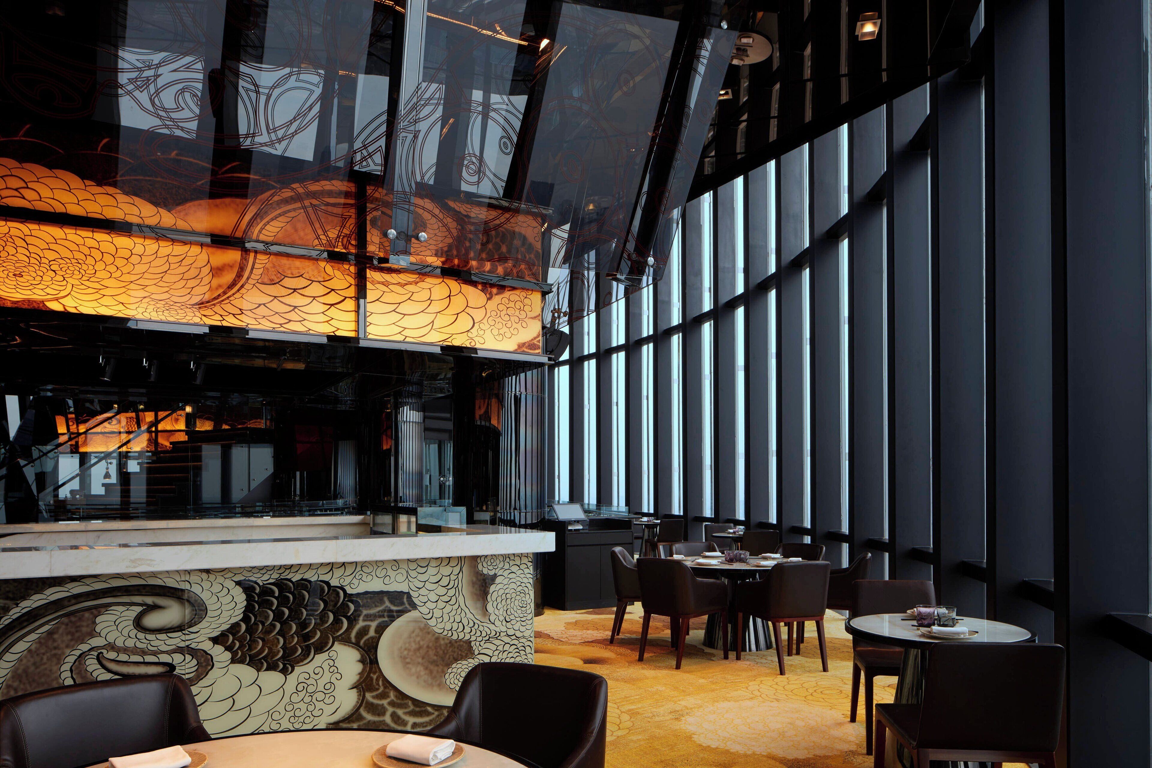 A modern interior with a dining area, a patterned wall, and large windows.