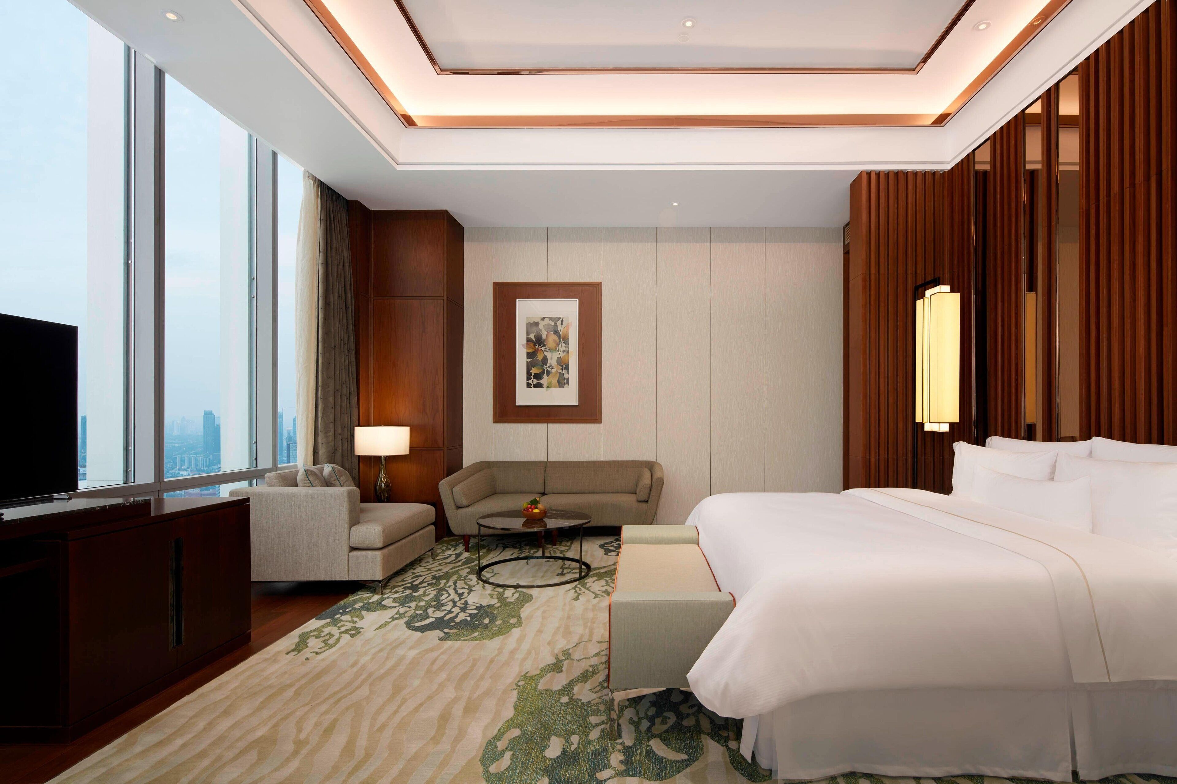 A hotel room with a large bed, a sofa, a small table, and a TV.